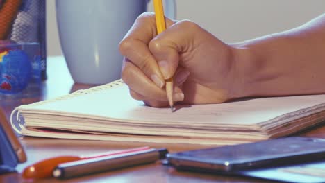 Dolly-shot-of-woman-working-at-home-office-hand-writing-on-note-book