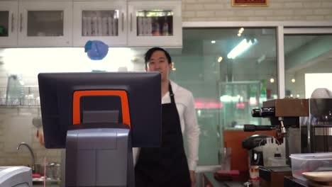 Young-Asian-male-café-barista-staff-welcoming-and-greeting-customers-in-the-café-restaurant