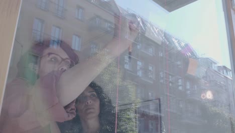 Two-businesswomen-brainstorm-on-windows-wall-over-real-estate