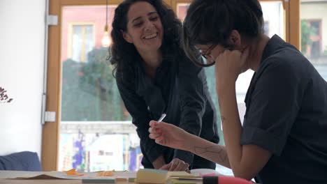 Two-business-women-brainstorm-together-with-electronic-device-on-a-casual-and-friendly-meeting