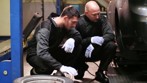 auto-mechanics-changing-car-tires-at-workshop