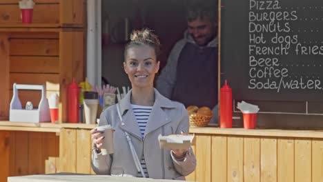 Mujer-feliz-compra-de-café-en-el-stand-de-alimentos