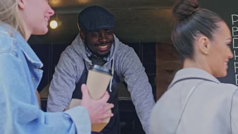 Smiling-seller-holding-out-order-to-clients-through-the-window-food-truck