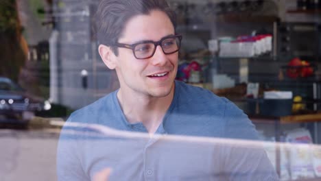 Three-young-adult-friends-talking-and-smiling-at-coffee-shop