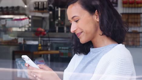 Young-female-using-her-smartphone-at-a-coffee-shop