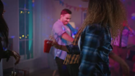 Auf-die-wilde-Hausparty:-hübscher-hispanischer-Kerl-tanzt-in-Neonlicht,-rote-Tasse-mit-Getränk.-In-den-Hintergrund-andere-Jugendliche,-die-Spaß,-Clubbing.