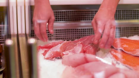 male-seller-putting-fish-fillet-to-fridge-at-shop