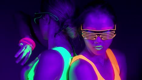 Langsame-Motin-von-schönen-sexy-Frauen-mit-fluoreszierenden-Make-up-und-Kleidung-Tanz-im-Neonlicht.-Night-Club,-Party-Konzept.