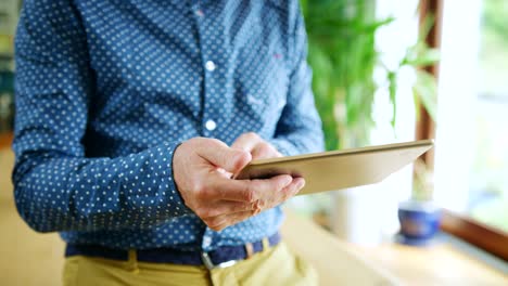 Businessman-Swiping-Through-Digital-Tablet-At-Home-Office