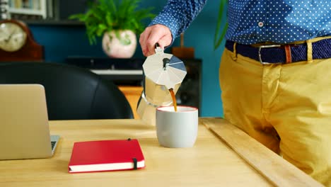 Geschäftsmann-gießt-die-Tasse-Kaffee-in-seinem-Heim-Büro