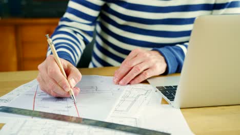 Architect-Working-On-Construction-Design-Blueprints-At-His-Desk