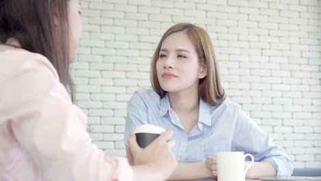 Asian-business-women-enjoying-drinking-warm-coffee,-discuss-about-work-and-chit-chat-gossip-while-relax-working-in-office.-Smart-business-women-social-meeting-concept.