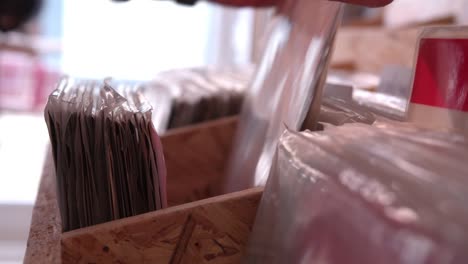 Close-up-of-hands-sorting-through-records-at-a-record-shop