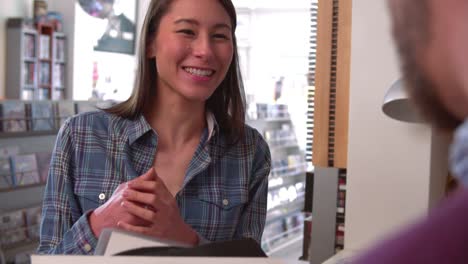 Young-woman-paying-at-the-counter-of-a-record-shop,-close-up