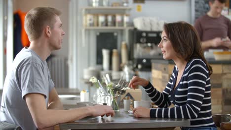 Adult-couple-talking-at-a-table-in-a-coffee-shop,-side-view