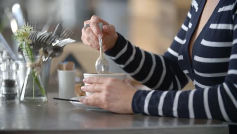 Nahaufnahme-von-Frauenhand-rühren-Tasse-Kaffee-in-einem-café