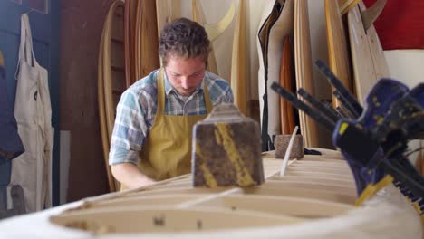 Man-Shaping-Custom-Surfboard-en-el-taller-filmado-en-la-cámara-roja