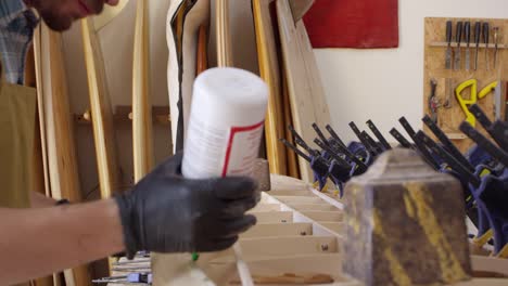 Man-Glueing-Custom-Surfboard-In-Workshop-Shot-On-RED-Camera