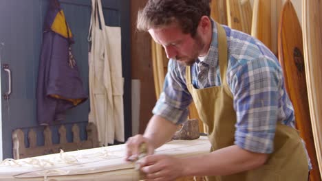 Man-Shaping-Custom-Surfboard-In-Workshop-Shot-On-RED-Camera