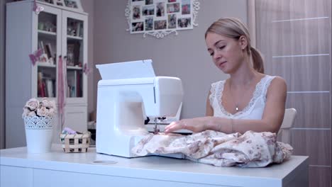 Attractive-young-woman-is-answering-her-phone-while-sewing