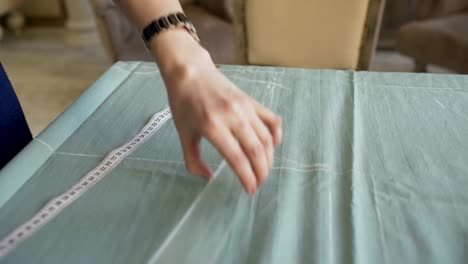 Seamstress-and-fashion-designer-at-work.-Young-woman-draw-chock-on-the-cloth-in-tailor-studio