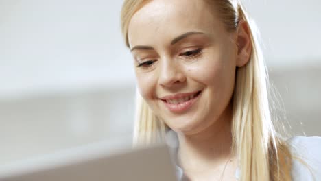 Nahaufnahme-des-Gesichts-eine-junge-schöne-Frau,-arbeitet-auf-einem-Laptop,-in-einer-hellen-Umgebung.