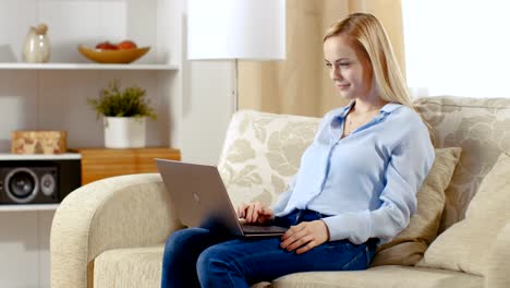 Young-Beautiful-Woman-Sitting-in-Her-Living-Room-and-Working-on-Her-Laptop.