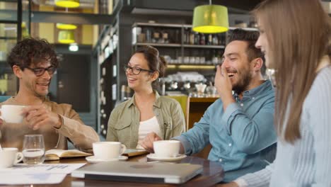 Pequeño-equipo-creativo-de-jóvenes-activos-que-tienen-reunión-y-discusión-en-la-cafetería.