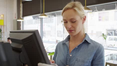 Waitress-Adding-Up-Bill-At-Cash-Register-In-Coffee-Shop