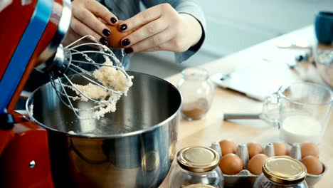 Nahaufnahme-der-jungen-weiblichen-Händen-mischen-der-Zutaten-in-eine-große-Schüssel-mit-Mixer.-Weiblich,-Kochen-in-der-Küche