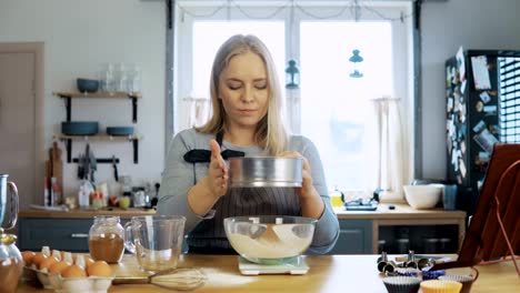 Mujer-hermosa-joven-pesa-el-cacao,-agrega-a-la-harina.-Chica-usando-escalas-de-la-cocina,-recipiente-y-tamiz-para-esto