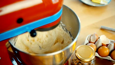 Close-up-view-of-red-mixer-blending-the-dough,-ingredients-in-big-bowl.-Confectioner-cooking-the-desserts