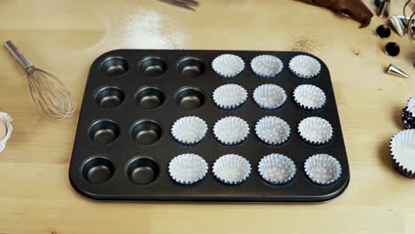 Nahaufnahme-des-weiblichen-Hand-setzen-die-Wrapper-Pappbecher-in-die-Auflaufform.-Frau-Kochen-Muffins.-Zeitraffer