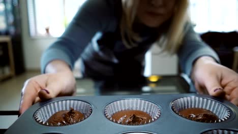 Vista-interior:-joven-abre-el-horno-y-poner-en-la-bandeja-para-cupcakes-de-la-hornada.-Mujer-bailando-mientras-espera-los-postres