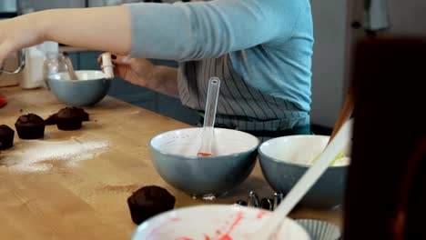 Young-blonde-woman-cooking-the-cupcakes-on-the-kitchen.-Beautiful-female-using-the-cutter-to-making-muffins