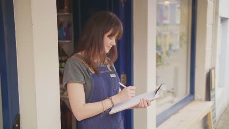 Escritura-de-propietario-Deli-sonriente-en-portapapeles-fuera-de-tienda