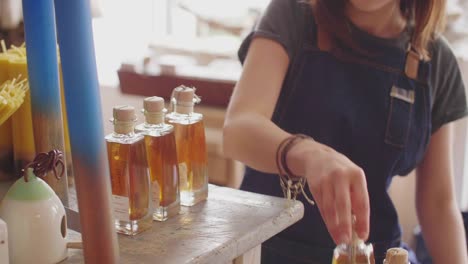 Midsection-Of-Deli-Owner-Arranging-Infused-Oil-Bottles-On-Counter