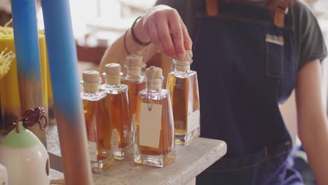 Small-Business-Owner-Arranging-Infused-Oil-Bottles-On-Counter