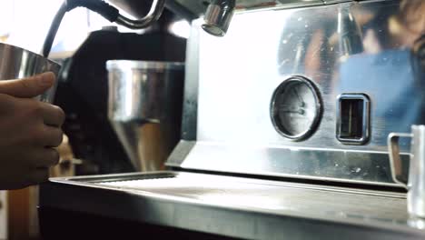 Barista-cociendo-al-vapor-la-leche-en-el-vaso-de-metal