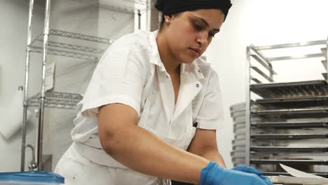 Masa-de-galletas-de-corte-mujer-hispana-en-una-panadería,-cerca