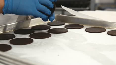 Baker-laying-out-cut-cookie-dough-on-a-baking-tray,-close-up