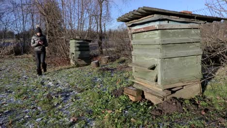 Frau-fotografieren-auf-Smartphone-in-der-Nähe-von-Bienenstock-im-winter