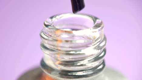 Taking-a-dip-from-manicure-bottle-on-foreground.-Pink,-transparent.