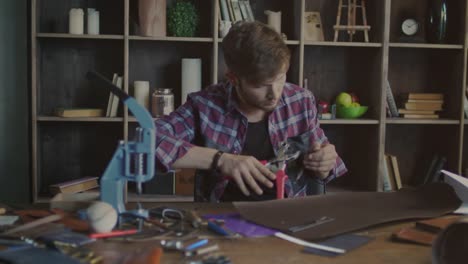 Fabricante-de-cuero-haciendo-corchete-del-metal-en-la-correa-de-cuero.-Pequeña-empresa