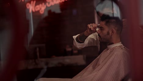 Man-getting-haircut-by-stylish-barber-in-old-fashioned-barber-shop