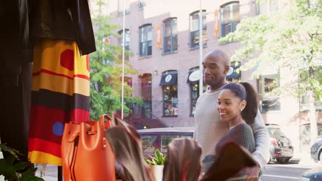 Smiling-couple-looking-in-a-clothes-shop-window