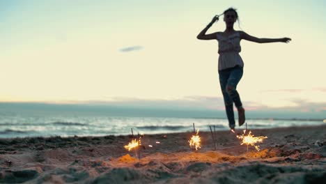 Teenager-Mädchen-mit-Wunderkerzen-tanzen-am-Strand.-in-Zeitlupe-erschossen