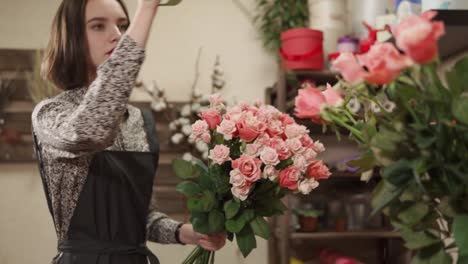 Junge-und-hübsche-Frau-macht-einen-Strauß-Rosen-für-den-Verkauf-in-einem-Blumenladen