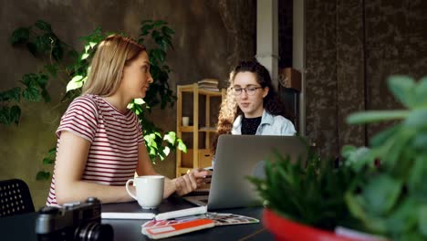 Starting-enterpreneurs-are-finishing-project,-checking-laptop-and-celebrating-success-with-high-five.-They-are-happy-and-optimistic-about-results-of-work.