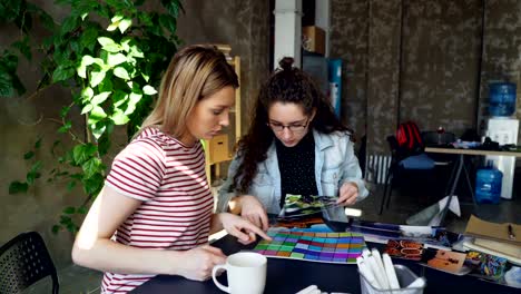 Creative-designers-are-watching-professional-photos-and-checking-color-palettes-comparing-colours-and-discussing-them.-Modern-loft-style-office-in-background.